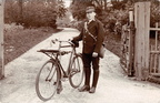 Charlie Curson, postman, with bicycle outside gateway and drive (? Barwick House), 1910s
