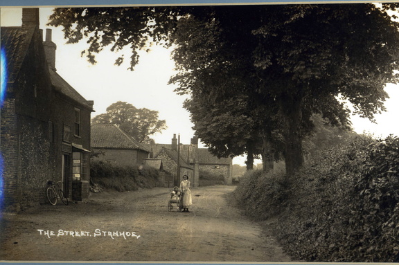 The Street, woman with pram outside the bakery (later Mrs Bloy's shop and now Fern Cottage). Postcard, c1920.